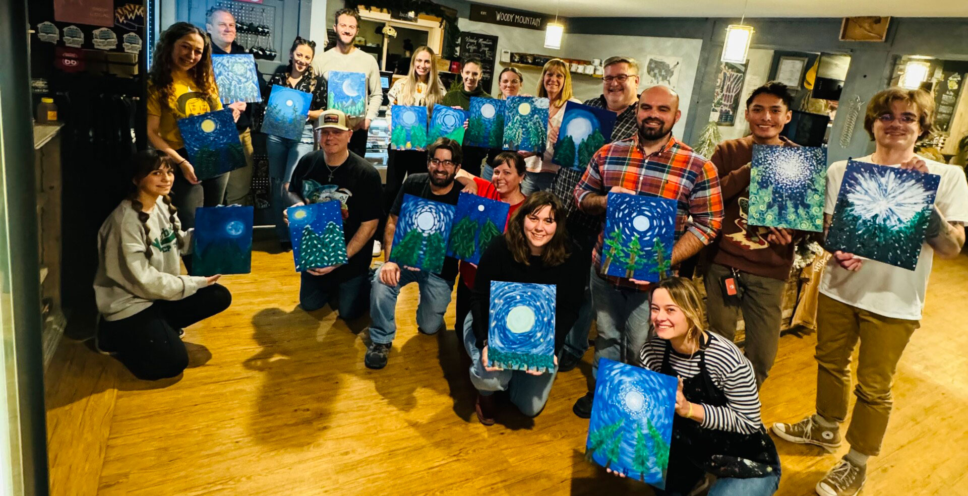 A group of people holding up their paintings. A group of people holding up their paintings.