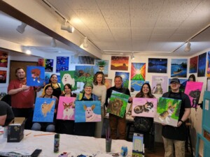 A group of people holding up their paintings.